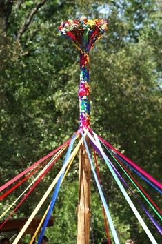 a pole that has some kind of colorful object on it's end and people around it