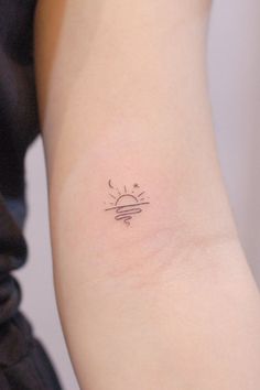 a woman's arm with a small sun and stars tattoo on the left side