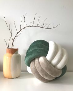 a vase with some branches in it next to a stack of towels on a table