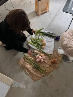 a woman sitting on the floor cutting up flowers