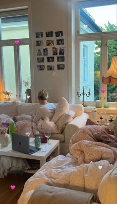 a woman sitting on top of a white couch in a living room filled with furniture