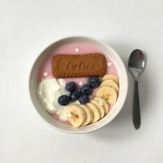 a bowl filled with bananas, blueberries and yogurt next to a spoon