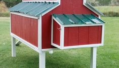 a red and white chicken coop in the grass