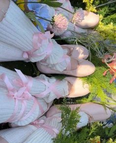 two pairs of feet in socks with pink bows and flowers on the ground next to them