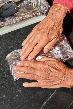 an older person's hands on aluminum foil