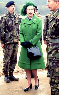 a woman in a green coat standing next to soldiers