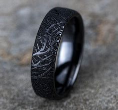 a black wedding ring with an intricate design on the inside is shown in close up