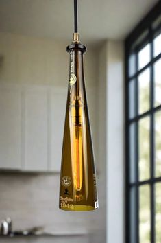 a wine bottle shaped light hanging from a ceiling fixture in a kitchen with an open window