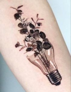 a light bulb tattoo on the arm with flowers in it and leaves growing out of it