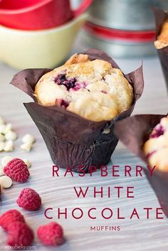 raspberry white chocolate muffins in wrappers on a table with berries