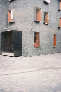 an open black box sitting in front of a brick building with windows on each side