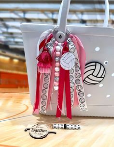 a white bag with pink tassels and beads hanging from it's handles