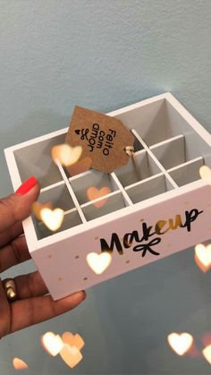 a person holding up a box with hearts on it and a tag that says makeup