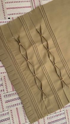 two pieces of cloth are laying on a quilted tablecloth with pins sticking out of them