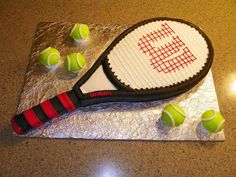 a cake made to look like a tennis racket and four balls on a table