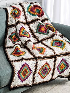 a crocheted afghan sitting on top of a blue couch next to a window