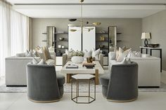 a living room filled with lots of furniture next to a tall white window covered in curtains