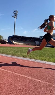 a woman is running on a track in the sun