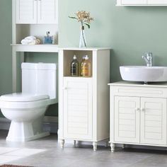 a white toilet sitting next to a sink in a bathroom under a window with green walls