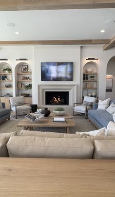 a living room filled with furniture and a flat screen tv mounted on the wall above a fire place