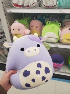 a person holding up a stuffed animal in front of shelves with cupcakes on them