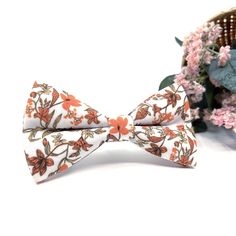 a bow tie with flowers on it sitting next to a basket and some pink flowers