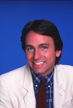 a man in a suit and tie smiling at the camera