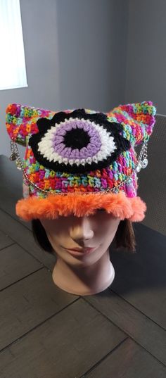 a white mannequin head wearing a multicolored hat with an evil eye on it