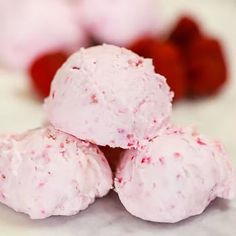 three scoops of ice cream sitting on top of a counter next to raspberries