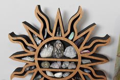 a wooden clock with rocks and crystals in the shape of a sun on a white wall