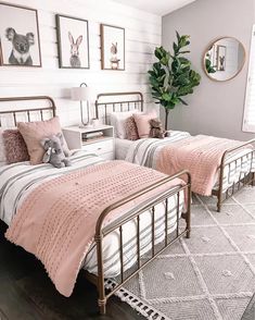 two beds in a bedroom with pink comforters and pictures on the wall above them