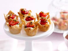 small cupcakes with strawberries and other toppings on a white cake plate