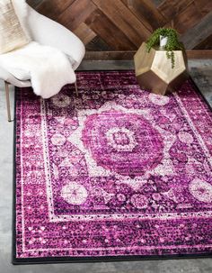 a purple area rug with an ornate design on the bottom and side, in front of a white chair