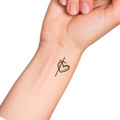 a woman's arm with a small tattoo on it that has a cross and heart in the middle