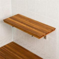 a wooden shelf in the corner of a white tiled bathroom with wood flooring and tile walls