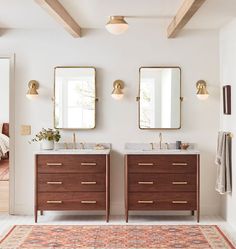 a bathroom with two sinks, mirrors and rug on the floor in front of it