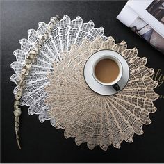 a cup of coffee sitting on top of a table next to a doily and a book