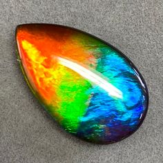 a multicolored piece of glass sitting on top of a gray floor next to a black object