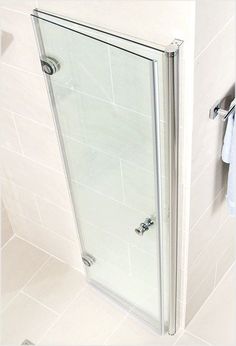 a glass shower door in a white tiled bathroom