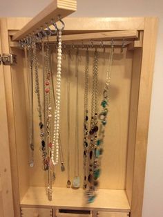 a wooden cabinet filled with lots of necklaces