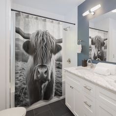 a cow shower curtain in a bathroom next to a toilet and sink with a large mirror