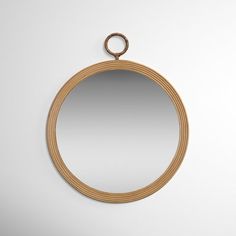 a round mirror hanging on the wall with a loop around it's edge and a ring at the bottom