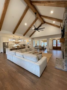 a large living room with wood beams and ceiling fan in it's center area