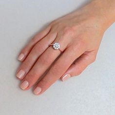 a woman's hand with a diamond ring on top of her left hand, against a white background