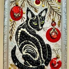 a black cat sitting on top of a table next to ornaments