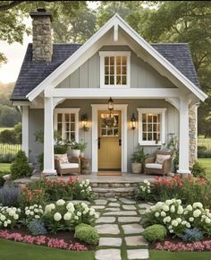 a small house with flowers and plants around the front door is featured in this image