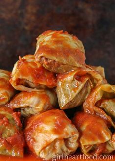 stuffed cabbage rolls piled on top of each other with sauce in the middle and meat filling