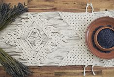 a wooden bowl filled with lavender on top of a white place mat next to two stalks of lavender