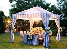 an outdoor tent set up for a party with blue and white linens on it