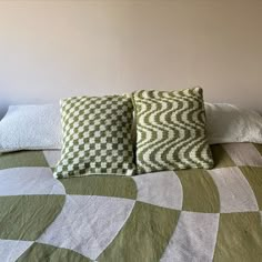 two pillows sitting on top of a bed covered in green and white checkered blankets